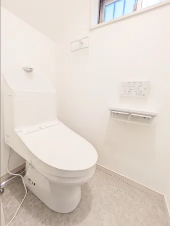 清潔感のある白を基調としたトイレです。温水洗浄便座付き、収納が設けられており、トイレットペーパーのストックや掃除用品などが収納できます。