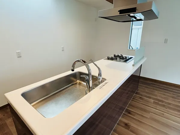 対面式のキッチン。広いシンクと3口コンロで、調理や片付けがしやすい印象です。