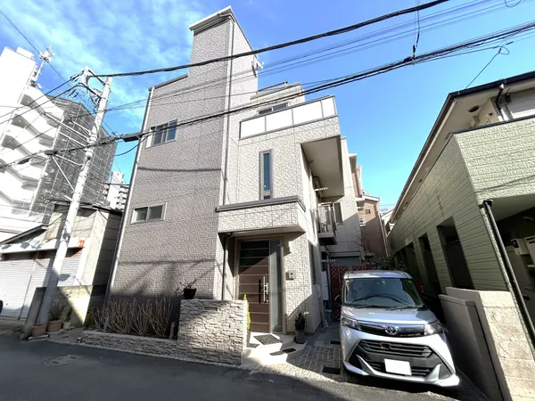 積水ハウス施工の賃貸併用注文住宅の外観です。タイル調の外壁と直線的なフォルムが印象的で、3階建て＋屋上の構成が街並みに調和しています。駐車スペースも確保されています。