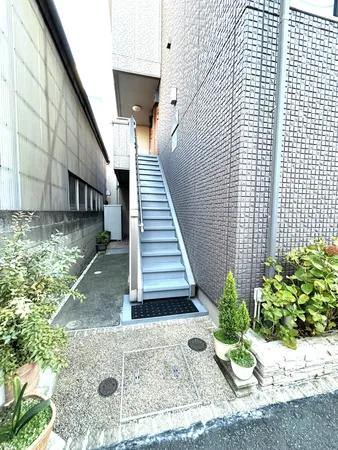 アパートエントランスは、植栽が彩りを添える明るい雰囲気です。階段は手すり付きで、安心して各住戸へアクセスできます。