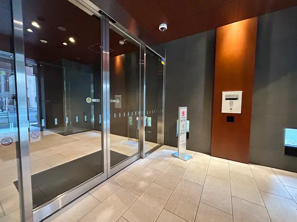 エントランスです。ガラス扉が設置され、外部からの視線を適度に遮りながらも、明るい光が差し込む空間となっています。オートロックやセキュリティカメラも設置されており、安心して暮らせる環境が整っています。