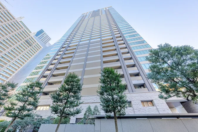 マンションの外観写真です。ガラス面が多く、バルコニー付きの住戸が並ぶ設計で、都市型の暮らしをイメージできます。エントランス周辺には植栽が施されております。