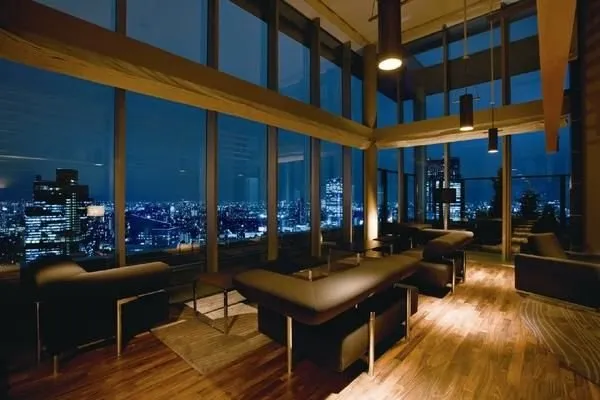 天井まで届く大きな窓が特徴のトップラウンジです。夜景を一望できる開放的な空間で、複数のソファセットが配置されており、ゆったりとくつろげる印象です。