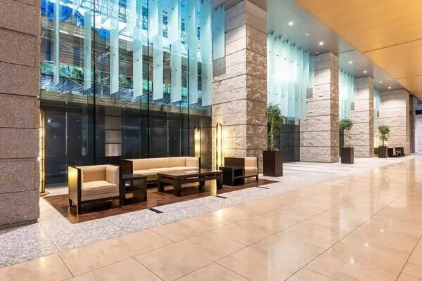 天井が高く、開放感のあるロビーです。大きなガラス窓から自然光が入り、明るい雰囲気が広がります。ゆったりとしたソファセットが配置されており、来客時や待ち合わせにも利用しやすい空間です。