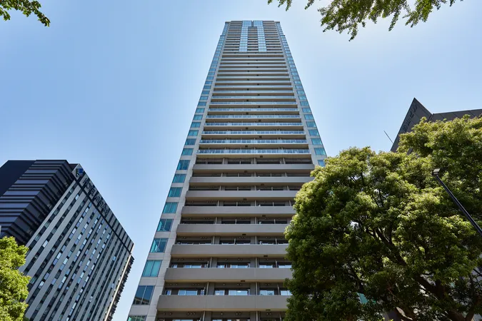 マンションの外観写真です。ガラス面が多く、バルコニーが各階に設けられているため、採光や眺望に配慮された設計がうかがえます。周囲には緑も多く、都市の利便性と自然の調和を感じられる環境です。