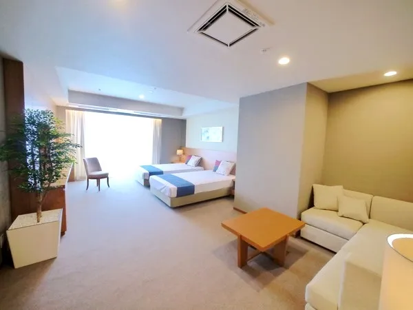 ゲストルーム。2台のベッドとソファが配置され、広々とした空間です。