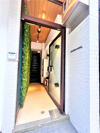 白を基調とした外壁と木目天井が調和したエントランスです。左側にはグリーンウォールが設けられ、自然の雰囲気を感じられる空間となっています。