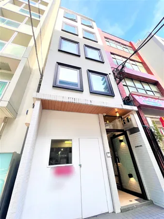 白を基調とした外観が印象的な建物です。大きな窓が複数並び、各フロアに明るい自然光が届く設計になっています。エントランスはガラス扉と照明付きの壁面で、清潔感と安心感が感じられます。