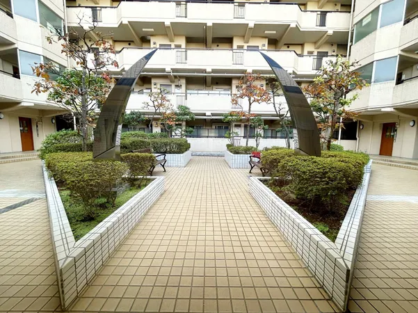 植栽とベンチが配置された中庭。開放感があり、休憩や散歩に適した共用スペースです。