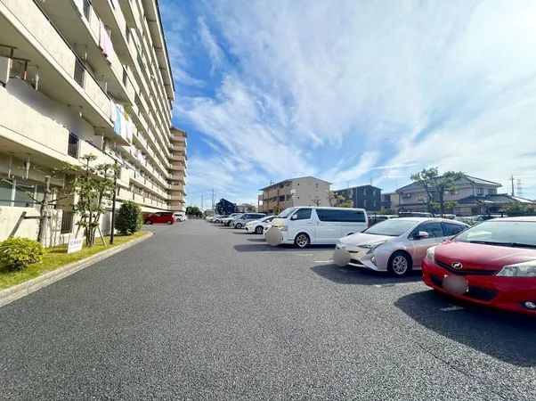 マンション敷地内の平面駐車場。広々とした舗装スペースで車の出し入れがしやすい印象です。