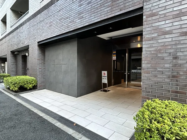 落ち着いた色調の外壁と、広めのエントランスアプローチが特徴的なマンションです。植栽が丁寧に配置されており、建物の重厚感と調和した印象です。