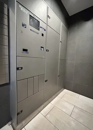 エントランスに設置された宅配ボックスの写真です。複数サイズのロッカーが備えられており、不在時でも荷物の受け取りが可能です。共用部の床や壁は落ち着いた色調で、清潔感のある空間となっています。