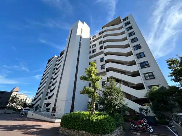 白を基調とした外観のマンション。敷地内に緑が配され、開放感のある印象です。