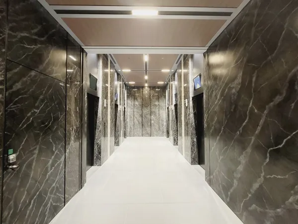 ブラックとグレーでまとめられた、シックな共用廊下。高層階用と低層階用でエレベーターが分けられています。