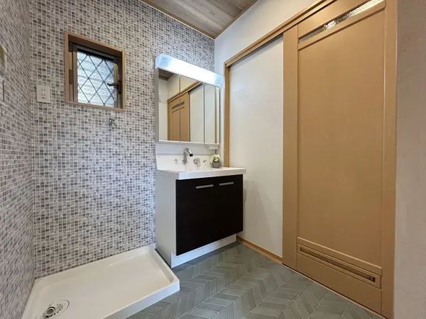 【洗面室】洗面室内には洗濯パンや洗面化粧台が設置されています。1階部分にあり、衛生面にも配慮された間取りとなっています。※写真中の家具・家電は売買価格に含まれません。