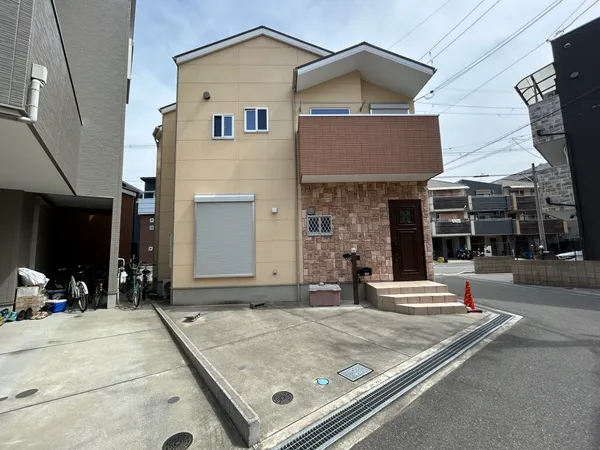 落ち着いた色合いの外観で、玄関前にはゆとりある駐車スペースが広がっています。道路に面した立地で、出入りがしやすく、来客時の案内もスムーズな印象です。