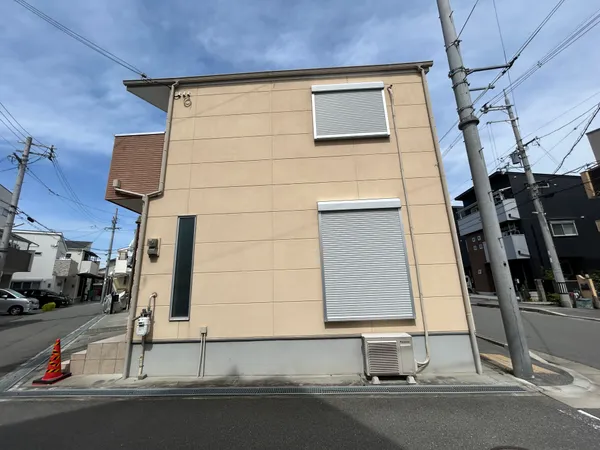 道路に面した側は窓がシャッターで覆われており、プライバシーと防犯に配慮された設計です。周囲は住宅街で、車通りが穏やかな印象を受けます。角地ならではの開放感があり、日当たりや通風にも期待できそうです。