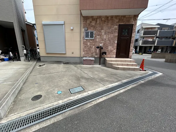 建物の玄関前には広めのコンクリート敷きスペースがあり、駐輪や来客時の一時駐車にも利用しやすい印象です。