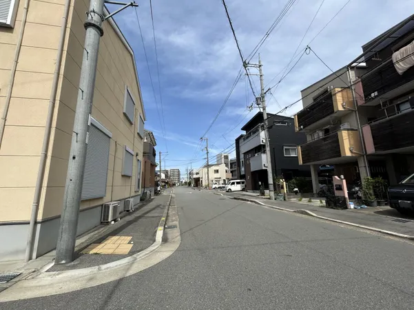 幅員のある前面道路の様子です。両側に住宅が並び、車の通行や歩行者の移動がしやすい印象です。電柱や植栽が適度に配置されており、周辺環境は落ち着いた雰囲気です。