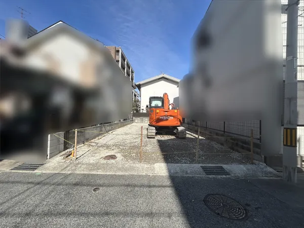 道路に面した敷地の写真です。幅員のある前面道路に接しており、車両の出入りや来客時の案内がしやすい印象です。両側には住宅が建ち並び、落ち着いた住環境が期待できそうです。