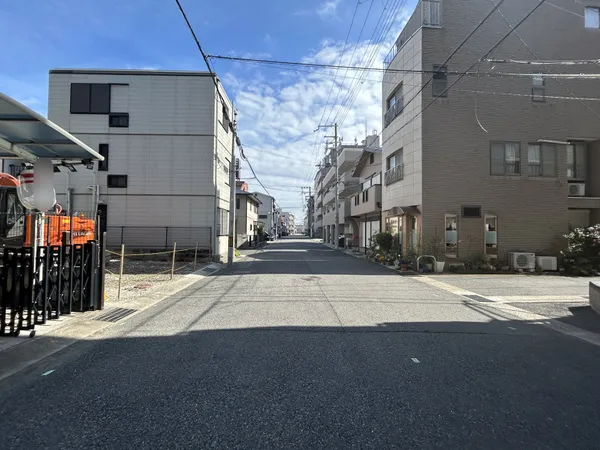 幅員のある前面道路は、両側に住宅や集合建物が並び、日中は明るい空が広がる印象です。歩道や植栽が整えられており、車の出入りや徒歩の移動もスムーズに感じられます。