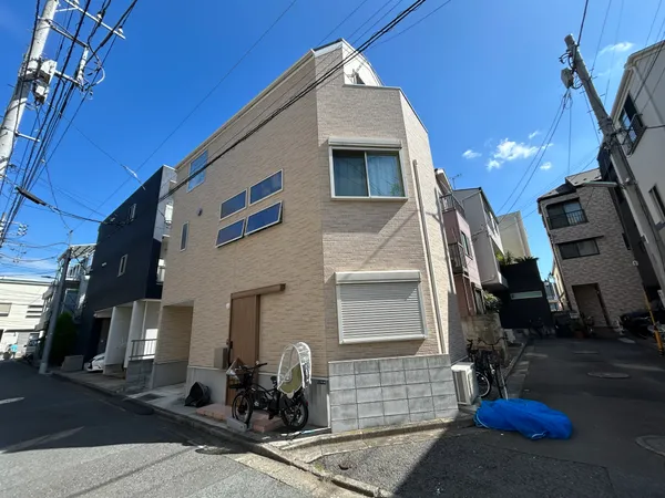 落ち着いた住宅街に建つ3階建ての戸建て。駐車スペース付き（車種による）で、外壁は明るい色調です。