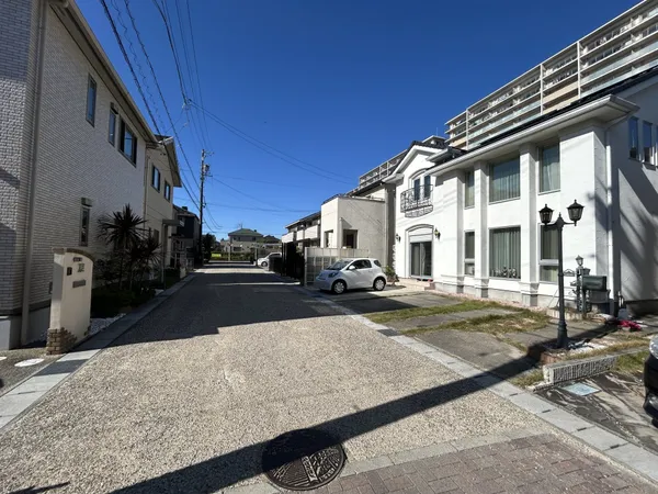 前面道路と住宅街の様子です。幅のある道路で車の出入りもスムーズに行えます。青空が広がり、周辺は落ち着いた住環境です。