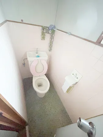 淡いピンク色のタイル壁のトイレ空間です。落ち着いて使用しやすい印象です。