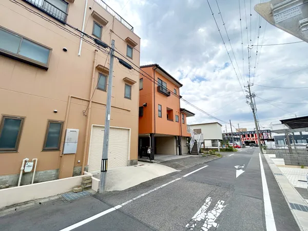 建物は落ち着いた色合いの外壁で、周囲の住宅と調和した印象です。前面道路は幅員があり、車の出入りや歩行も安心感があります。