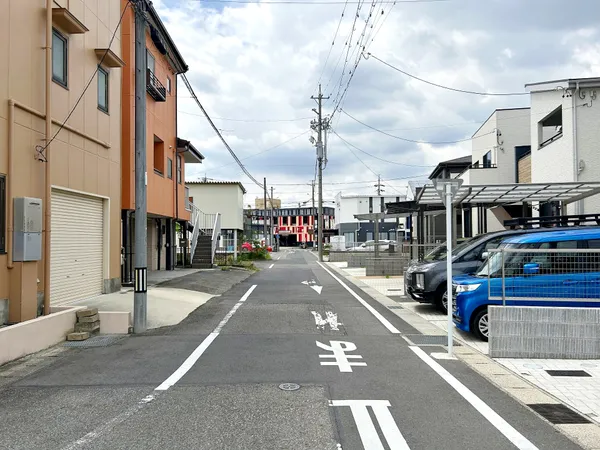 幅員がしっかり確保された前面道路の様子です。両側に戸建てや駐車場が並び、車の出し入れもしやすい印象です。
