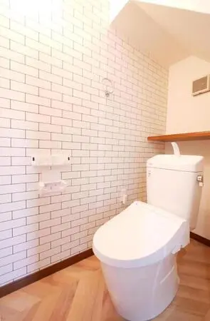 【トイレ】レンガ調のアクセントクロスがお洒落な空間です。トイレは、1年を通して快適に使用できる温水洗浄便座機能付き。トイレットペーパーや芳香剤などを置くことができる棚付きです。
