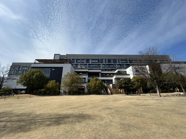 広々とした芝生広場と商業施設が一体となった外観です。開放感があり、周辺環境も整っています。