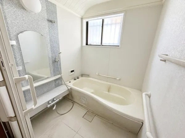 大きな窓から自然光が入る浴室。浴槽と手すりが設置され、使いやすい仕様です。