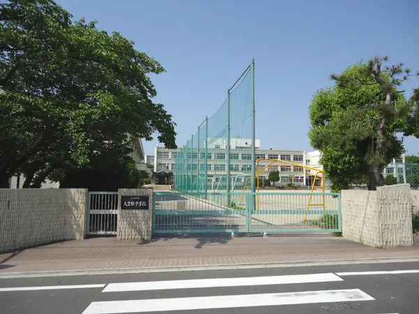 大曽根中学校の外観です。正門前には横断歩道があり、校庭には遊具やネットが設置されています。