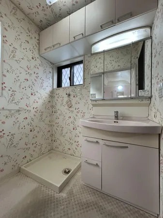 【1階洗面台】花柄クロスが華やかな洗面スペース。収納豊富なミラーキャビネットと広々カウンターで快適な身支度が可能です。