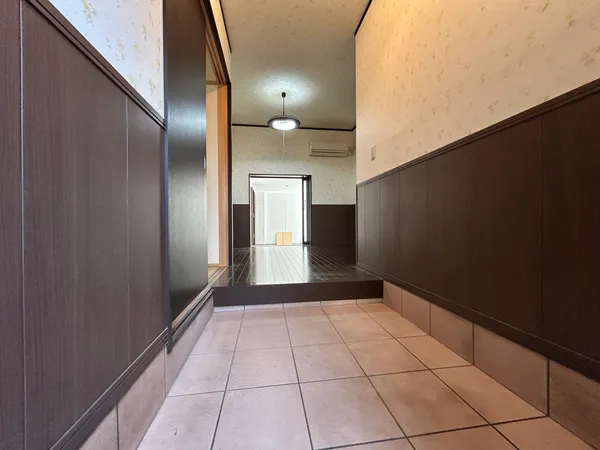 【土間】広々としたタイル敷きの土間空間。木目調の壁が落ち着きを演出し、テラスへと続く開放的なスペースで多用途に活用できます。