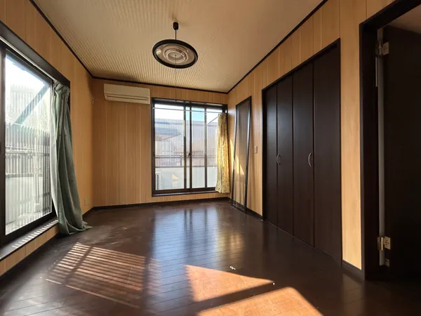 【洋室 約6.0帖】木目調の壁が温もりを演出する洋室。大きな窓から光が差し込み、収納充実で快適に過ごせる空間です。